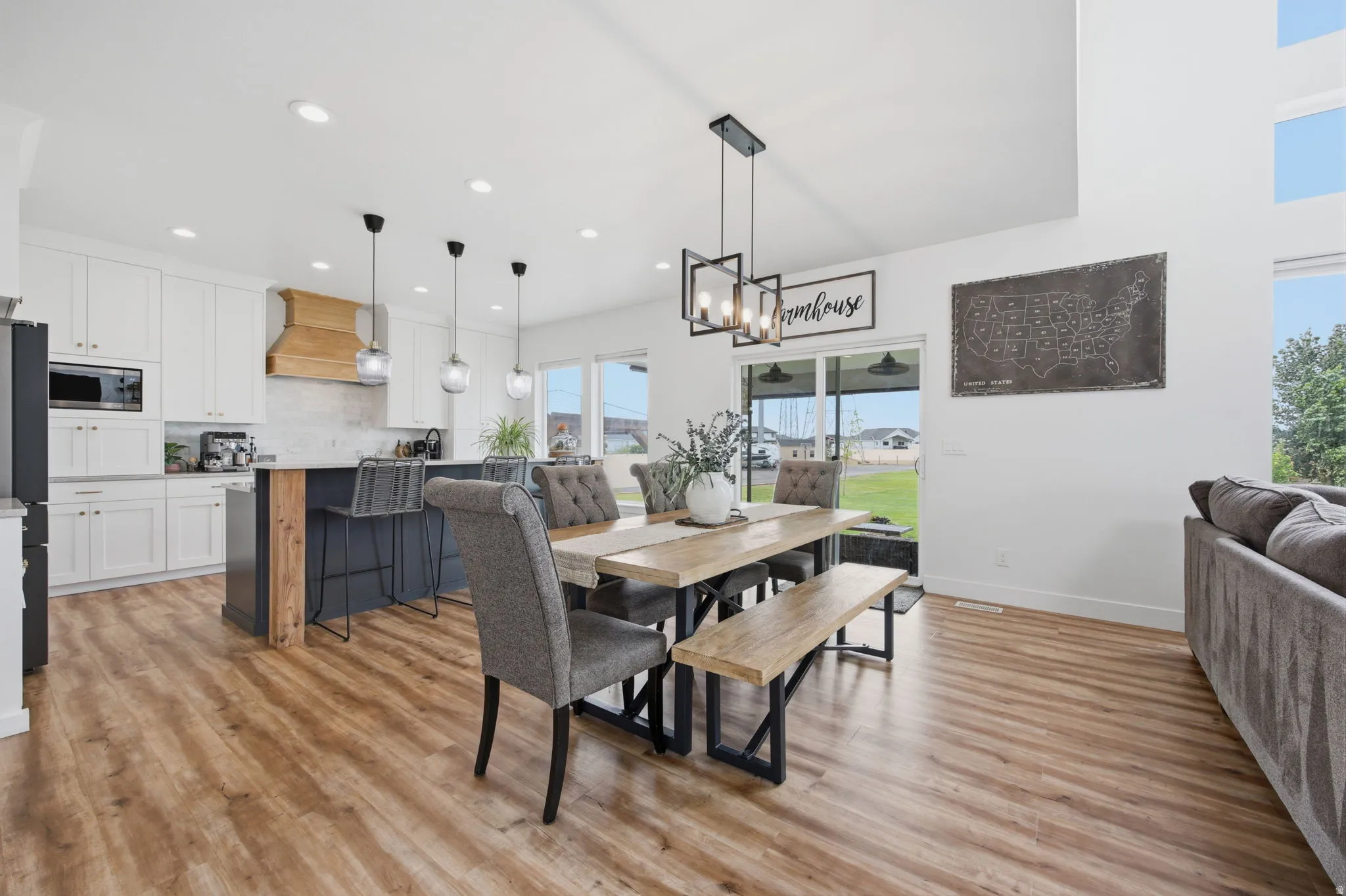 Spacious open-concept living area featuring wood-finish flooring, high vaulted ceilings, and large windows
