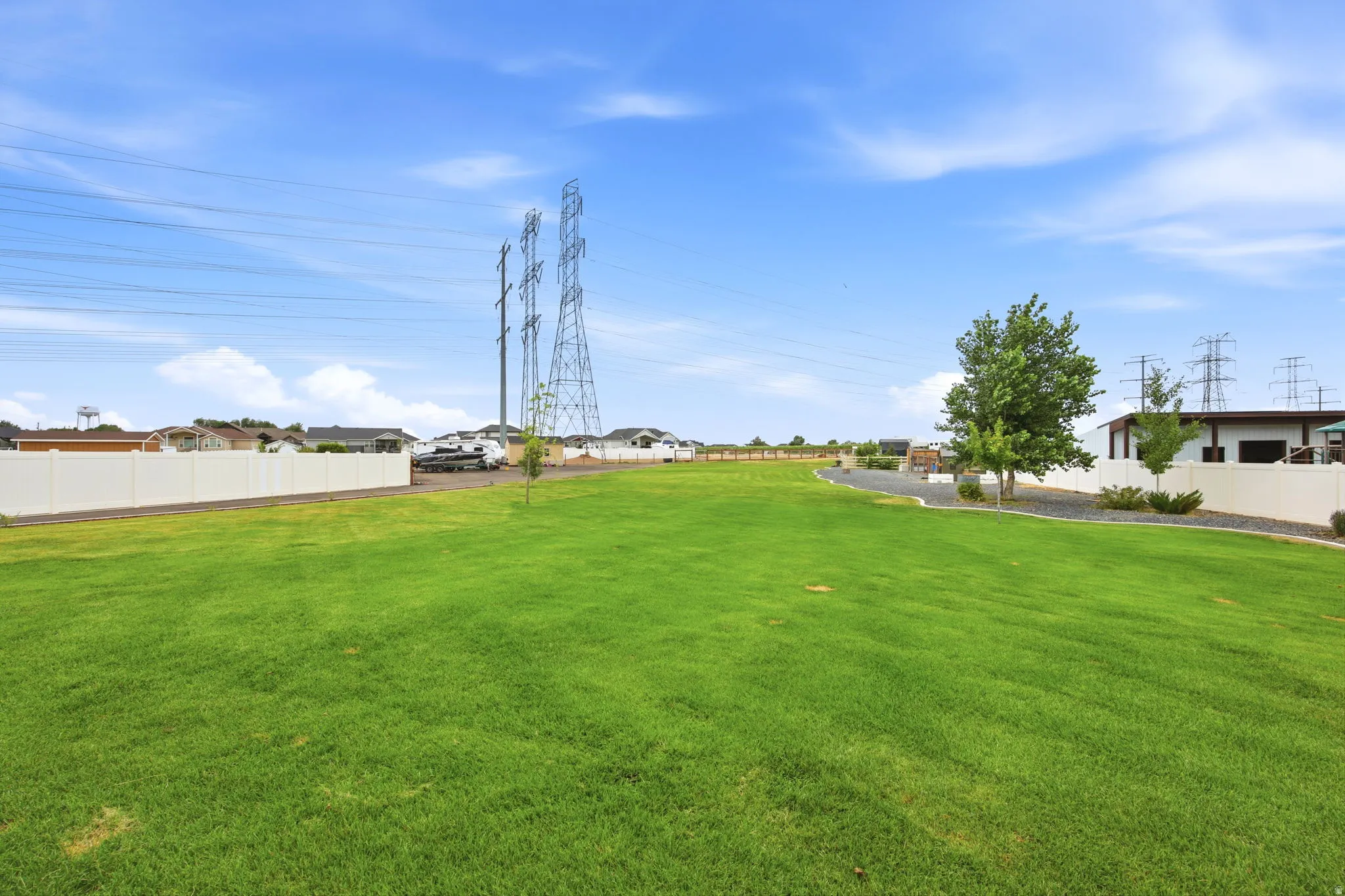 Expansive green lawn with a white privacy fence
