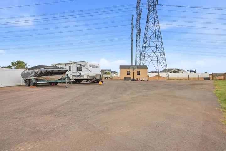 Expansive paved lot with a white privacy fence and a detached storage shed