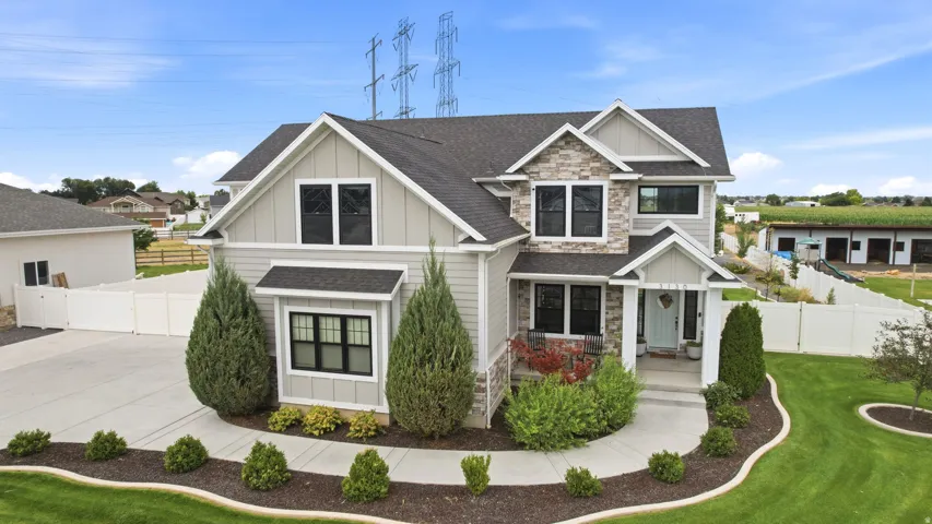 Contemporary dwelling featuring stone and siding exterior, dark framed windows, a covered front porch, and a concrete driveway