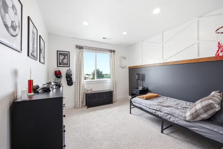 Spacious room featuring light-colored carpeting, recessed lighting, a large window with exterior scenery, a feature wall with a geometric panel design, and a contrasting dark accent wall with a wood-finish top trim