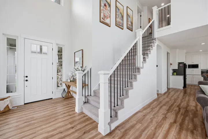 Two-story foyer featuring a staircase with black iron spindles, light wood-finish flooring, and a white front door with sidelights
