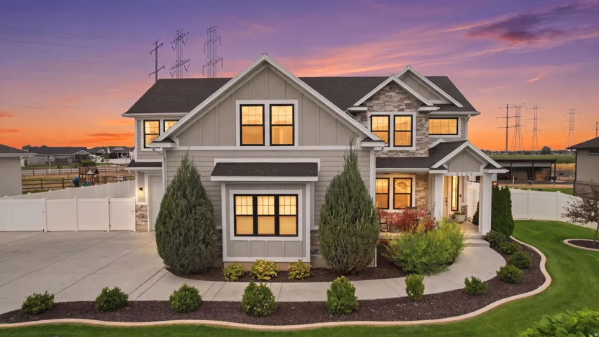 Two-story residence featuring a combination of siding and stone veneer, dark-framed windows, a concrete driveway, an arched walkway, and a manicured lawn