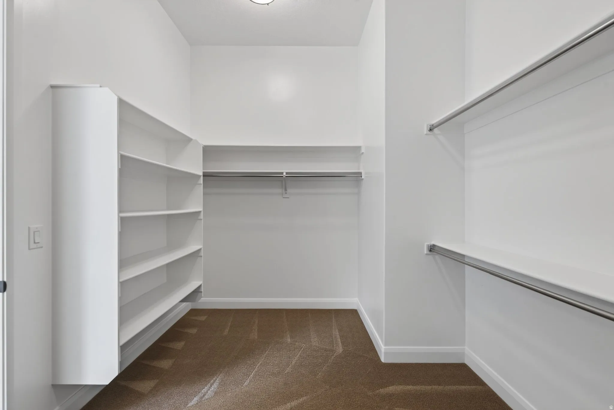 Walk-in closet featuring built-in shelving, multiple hanging rods, and plush carpeting