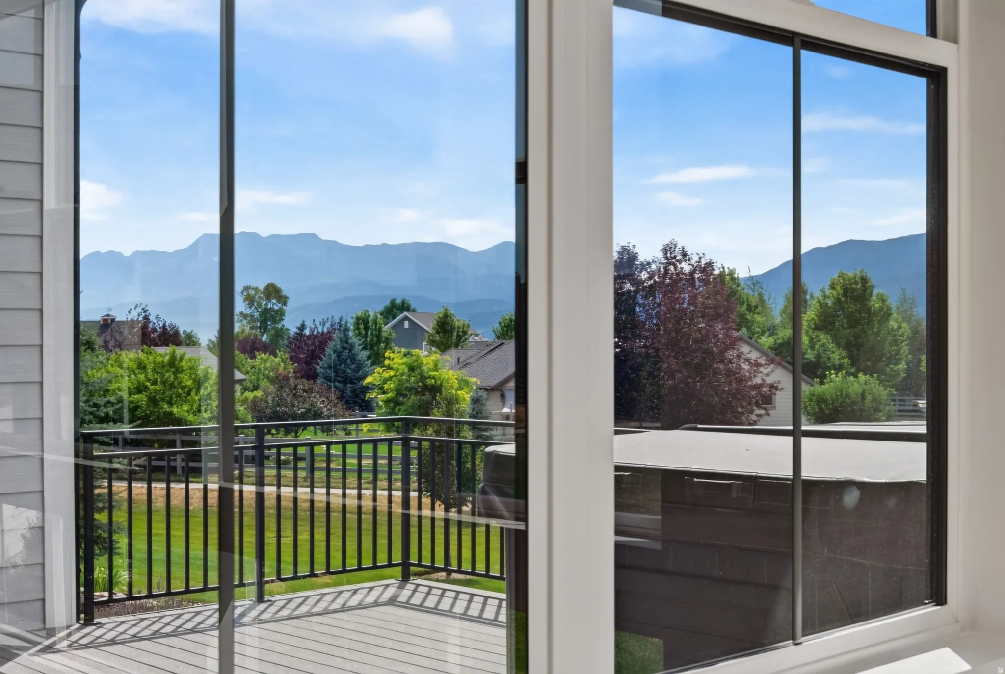 Expansive mountain scenery visible through large windows and a composite deck featuring black metal railings