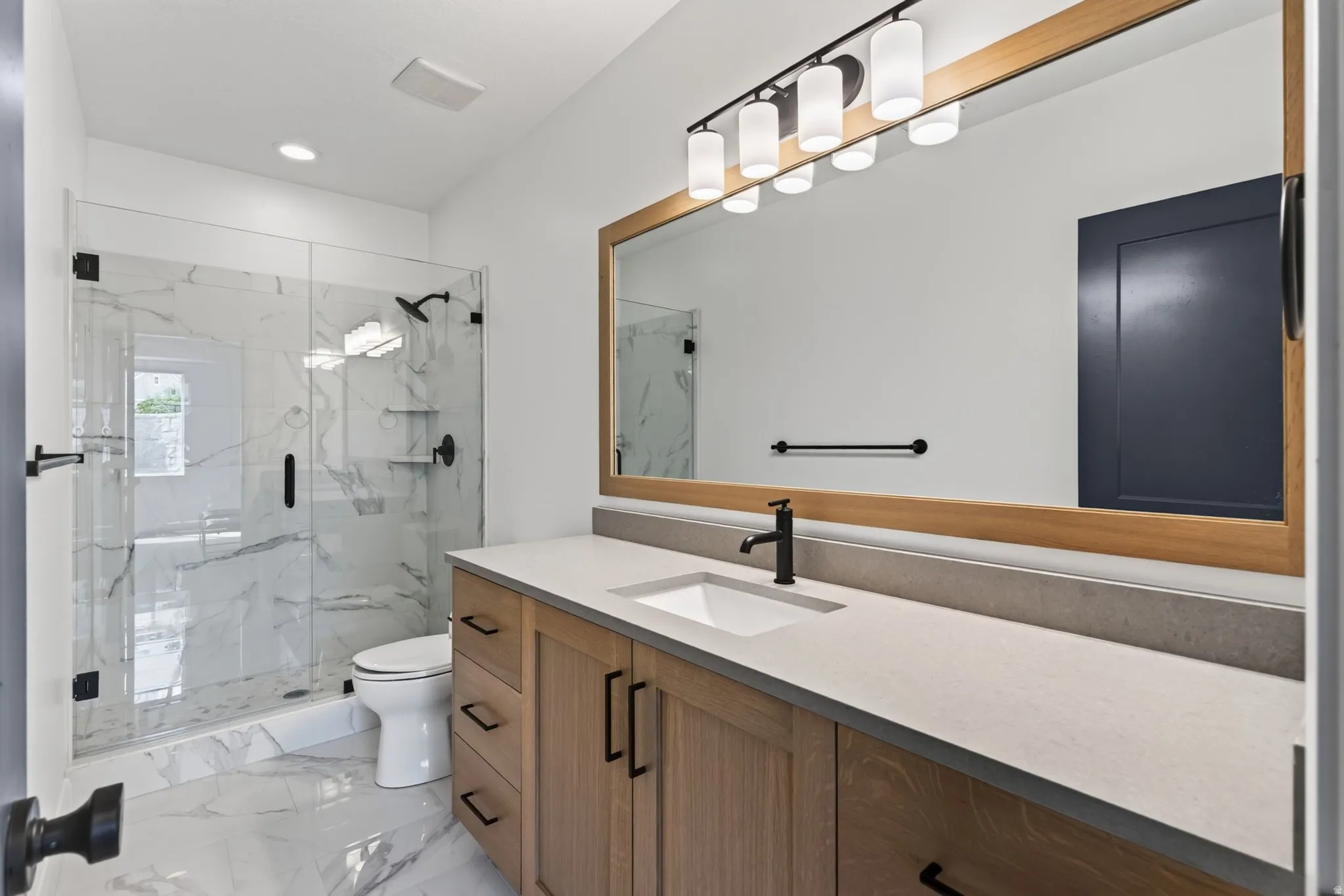 Modern bathroom featuring a single vanity with wood-finish cabinetry, a light-colored countertop, and a rectangular undermount sink