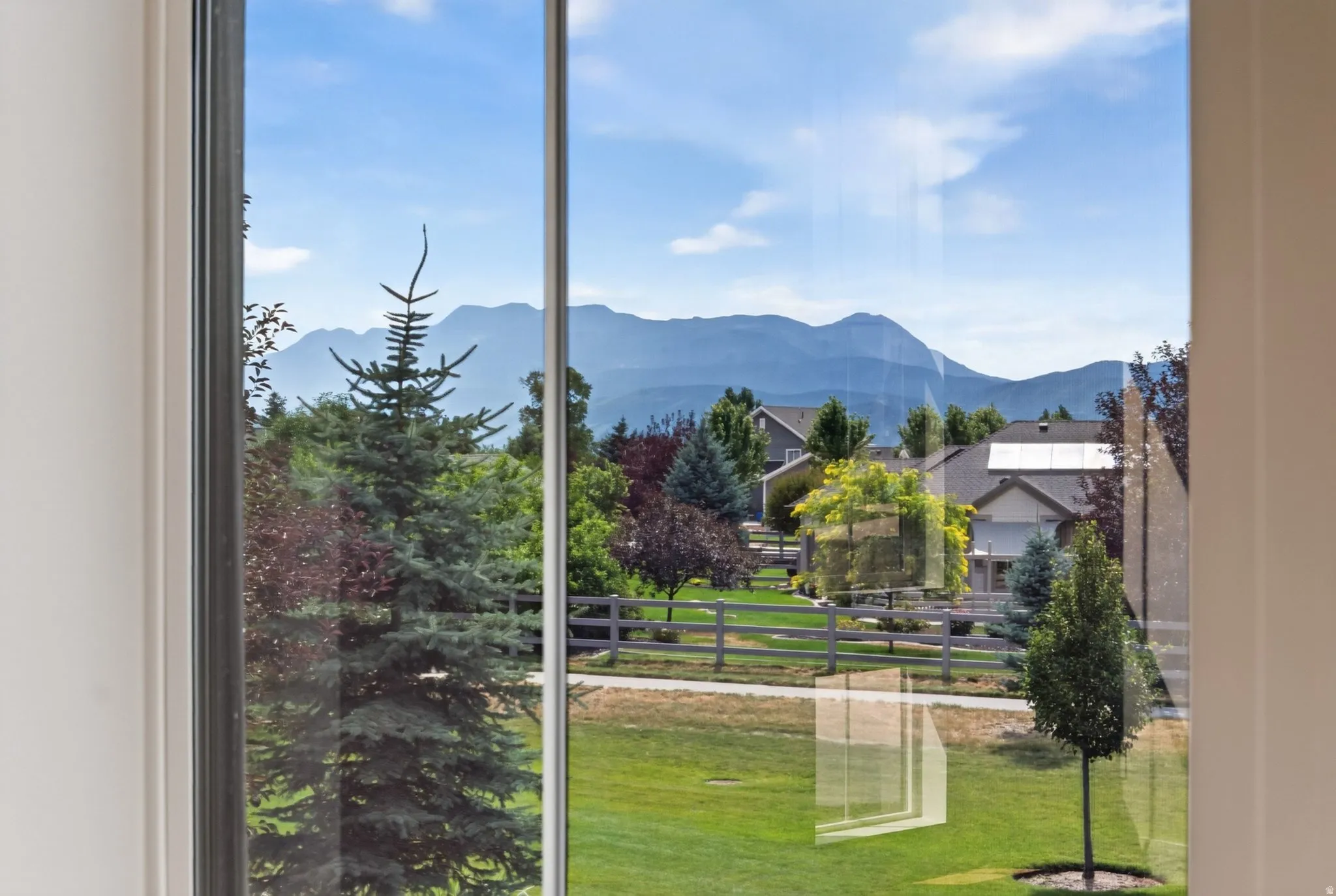 Framed mountain scenery with a lush green lawn and mature evergreen trees