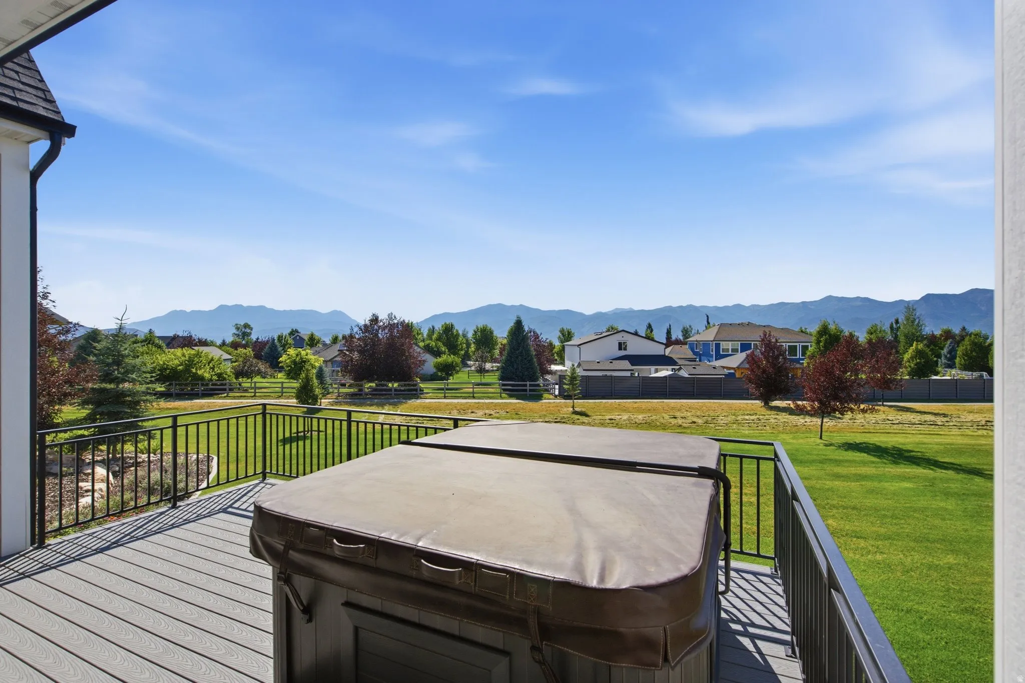Composite decking with black metal railing, featuring a built-in hot tub