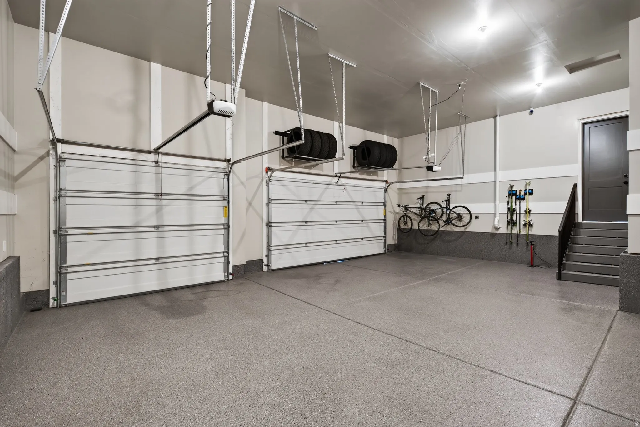 Spacious multi-car garage featuring a speckled epoxy floor coating and two overhead garage doors