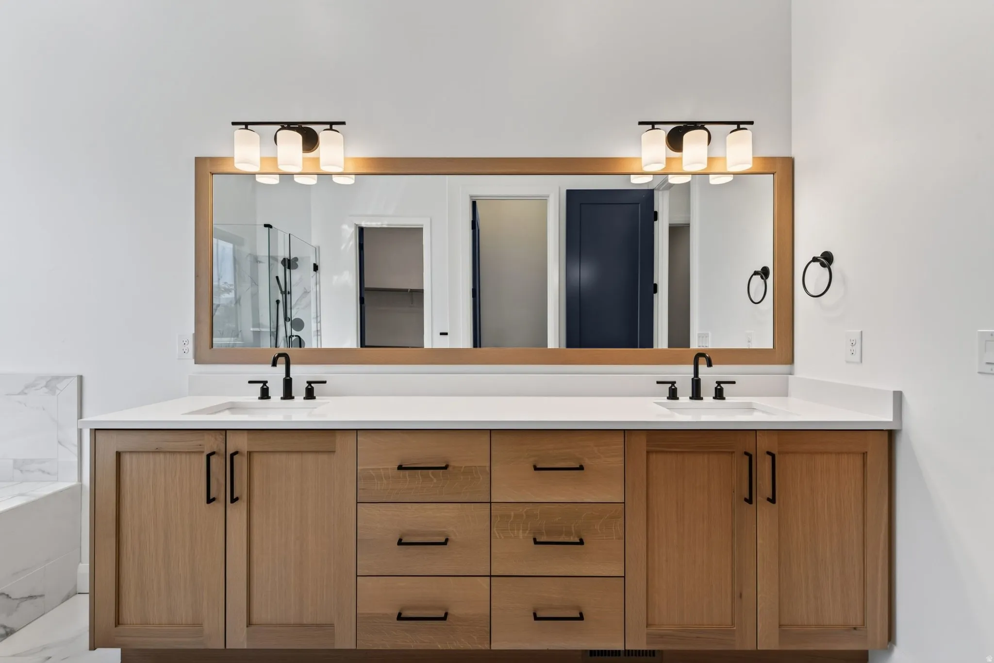 Double vanity with wood-finish cabinetry and matte black hardware