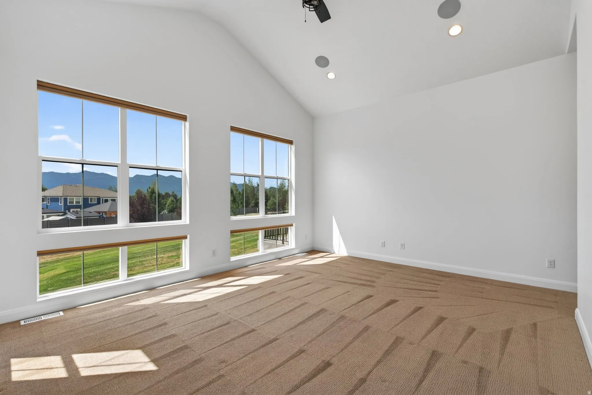 Expansive room featuring a vaulted ceiling and contemporary carpet flooring