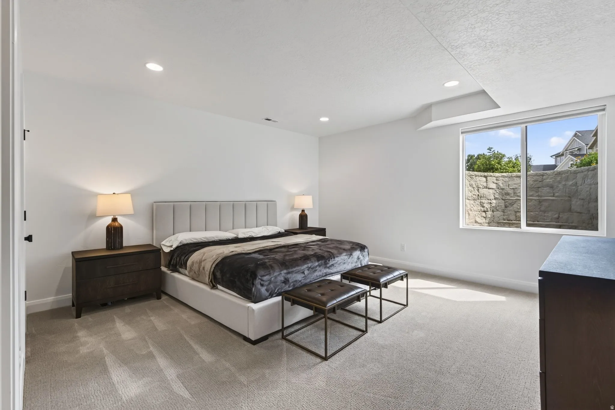 Spacious room featuring light-toned carpeting, recessed lighting, and a large window