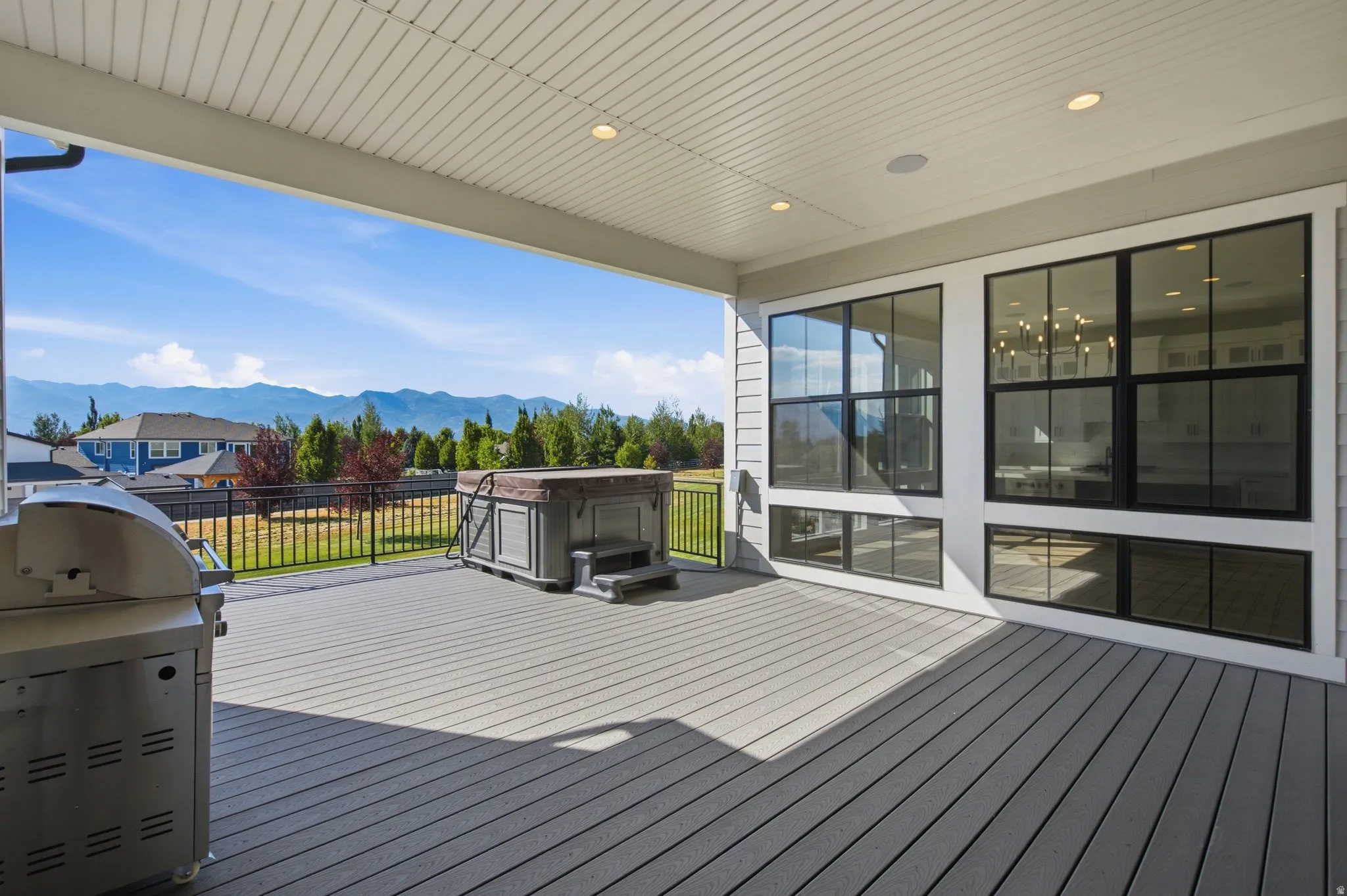 Covered outdoor deck featuring composite decking, a built-in hot tub, and an outdoor grill