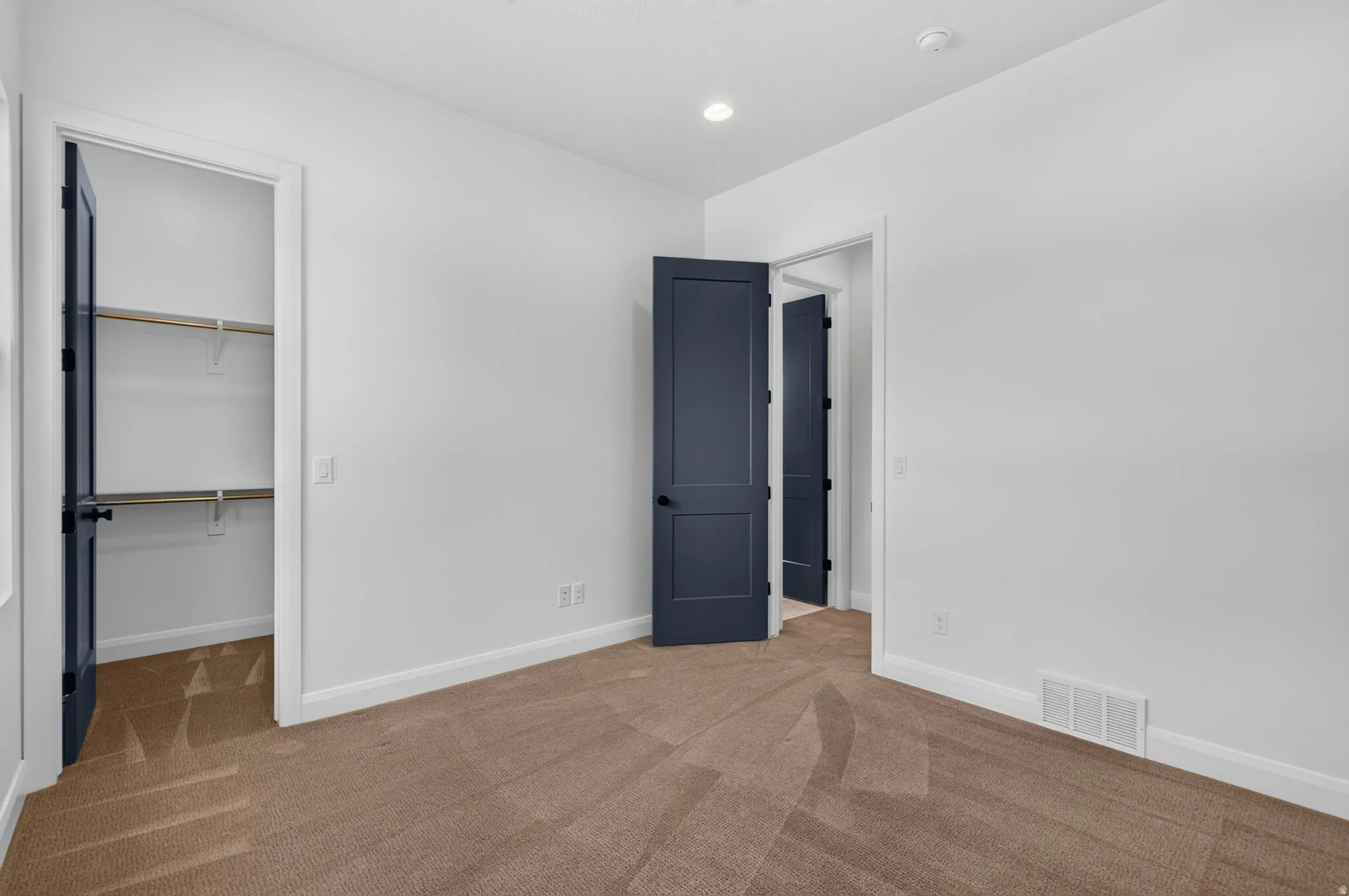 Interior room with light gray walls, plush brown carpeting, and a white ceiling with recessed lighting