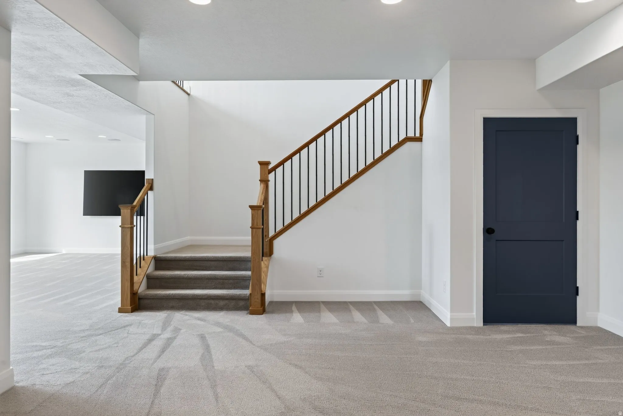 Staircase featuring wood newel posts, wood handrail, and black iron balusters