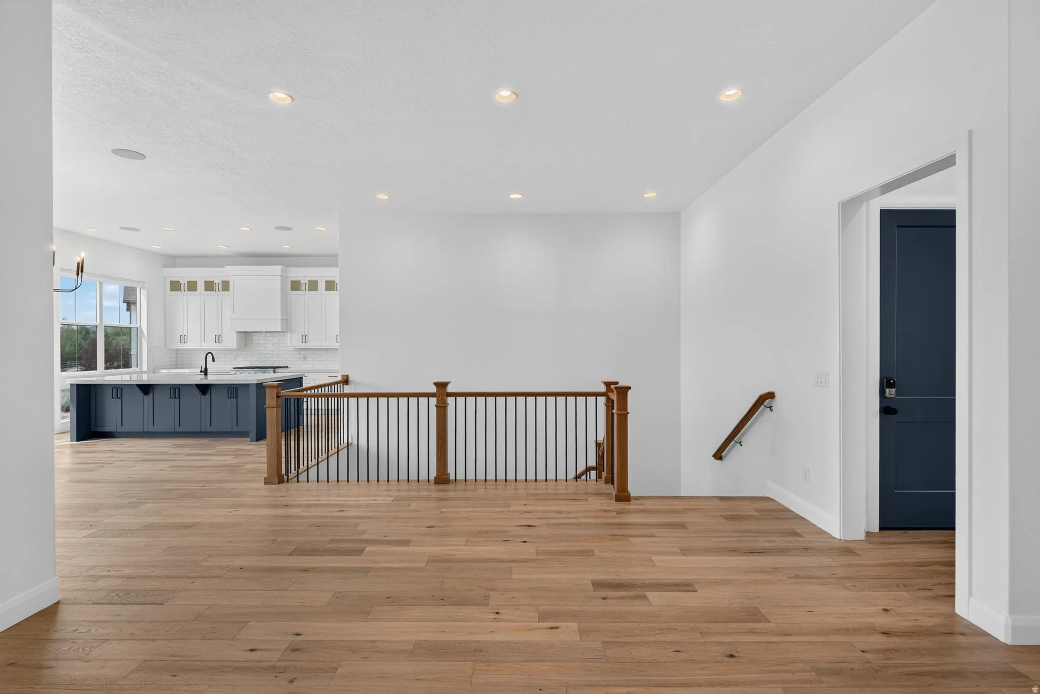 Open-concept living area with wood-finish flooring, recessed lighting, and a modern kitchen