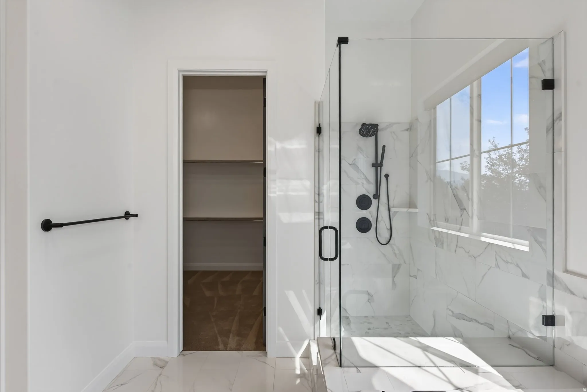 Spacious walk-in shower with clear glass enclosure and black matte fixtures