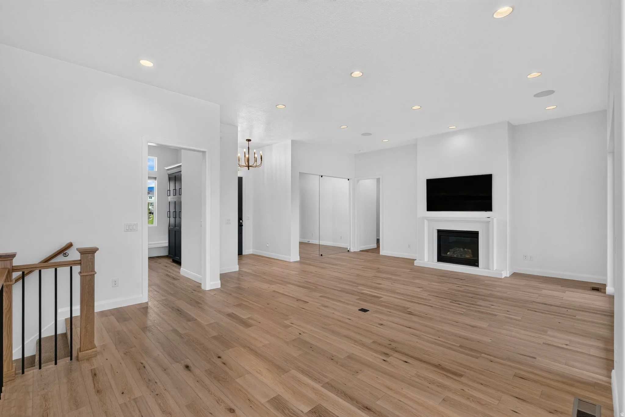 Spacious living area featuring wood-finish flooring, recessed lighting, and a white mantel fireplace with a dark insert