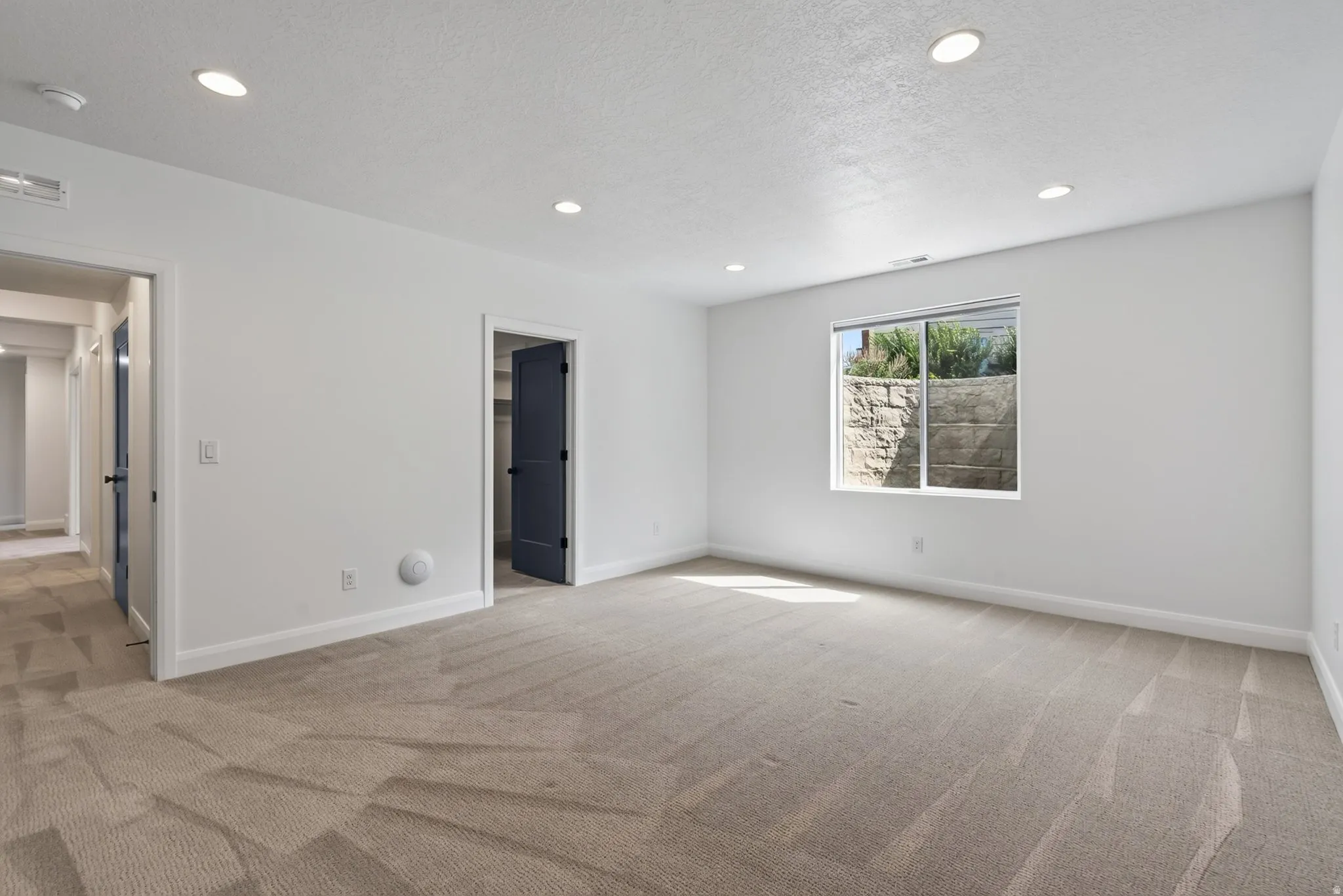 Spacious room featuring neutral carpeting, white walls, recessed ceiling lights, and white trim