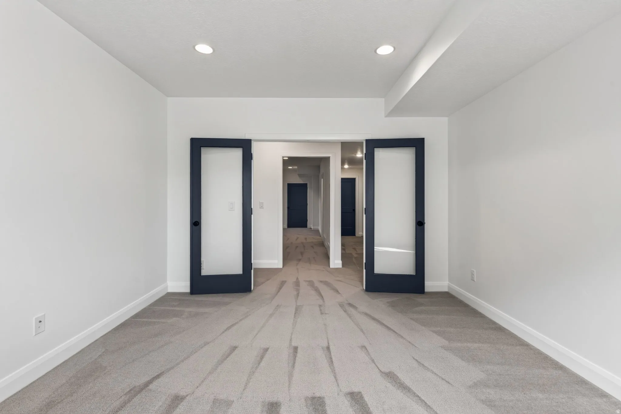 Spacious room featuring gray carpet, white walls, and recessed lighting