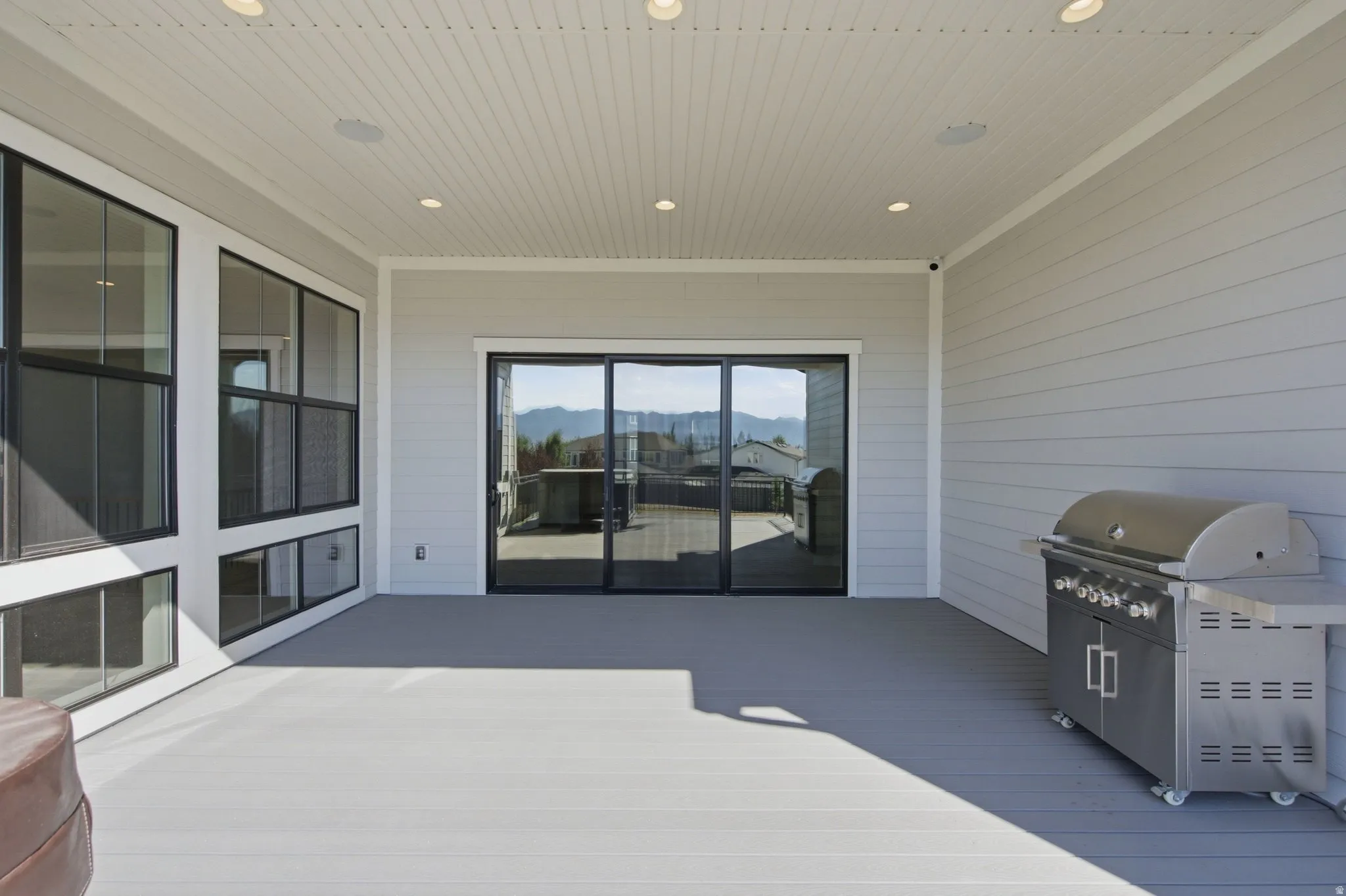 Expansive covered patio featuring light gray decking, recessed lighting, and integrated ceiling speakers
