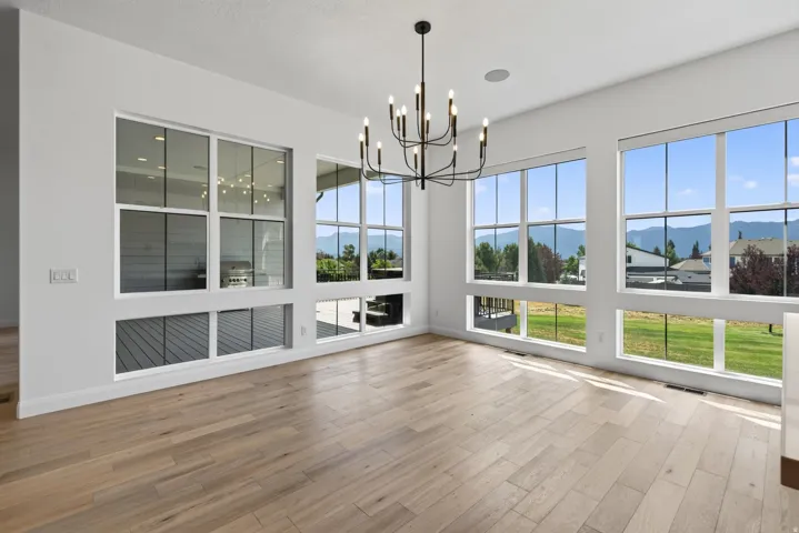 Spacious room featuring extensive window-lines, natural wood-finish flooring, and a contemporary black chandelier