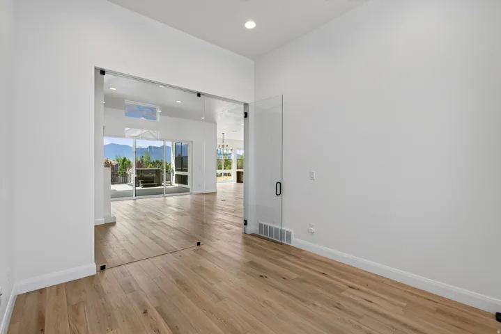 Interior space featuring full-height glass panel entry, wood-finish flooring, recessed lighting, and white walls