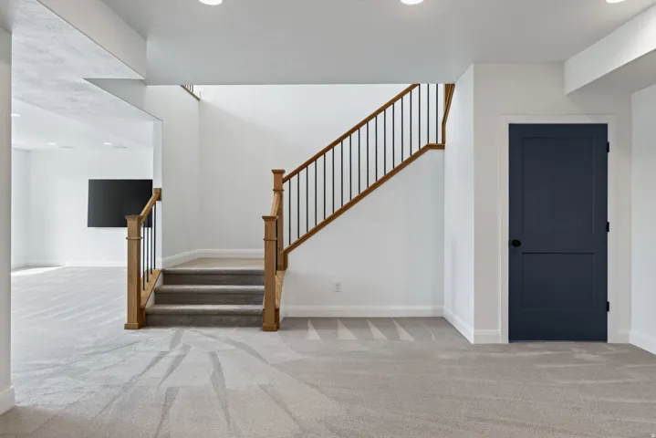 Staircase featuring wood newel posts, wood handrail, and black iron balusters