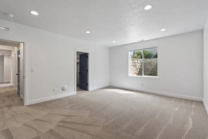 Spacious room featuring neutral carpeting, white walls, recessed ceiling lights, and white trim