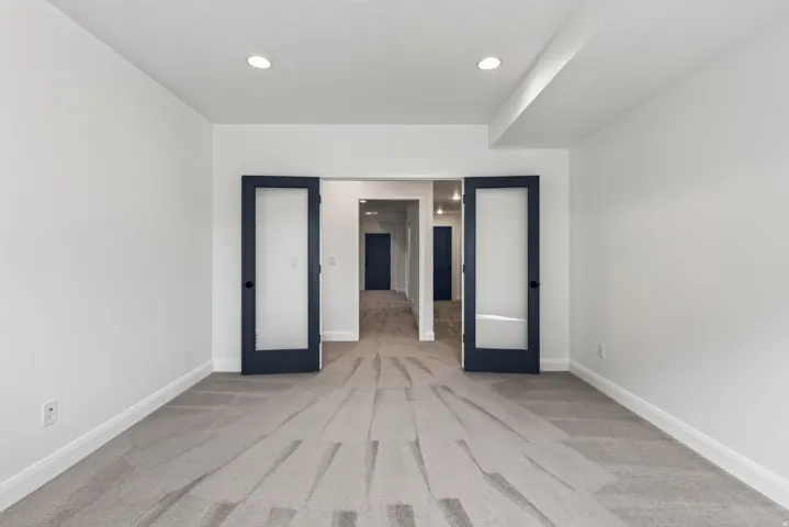 Spacious room featuring gray carpet, white walls, and recessed lighting