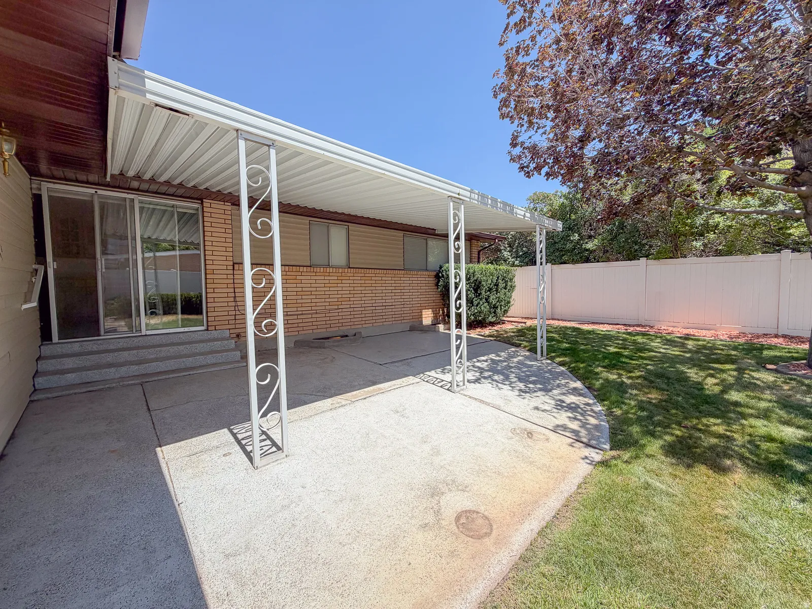 Covered patio with concrete surface, brick exterior wall, and sliding glass doors