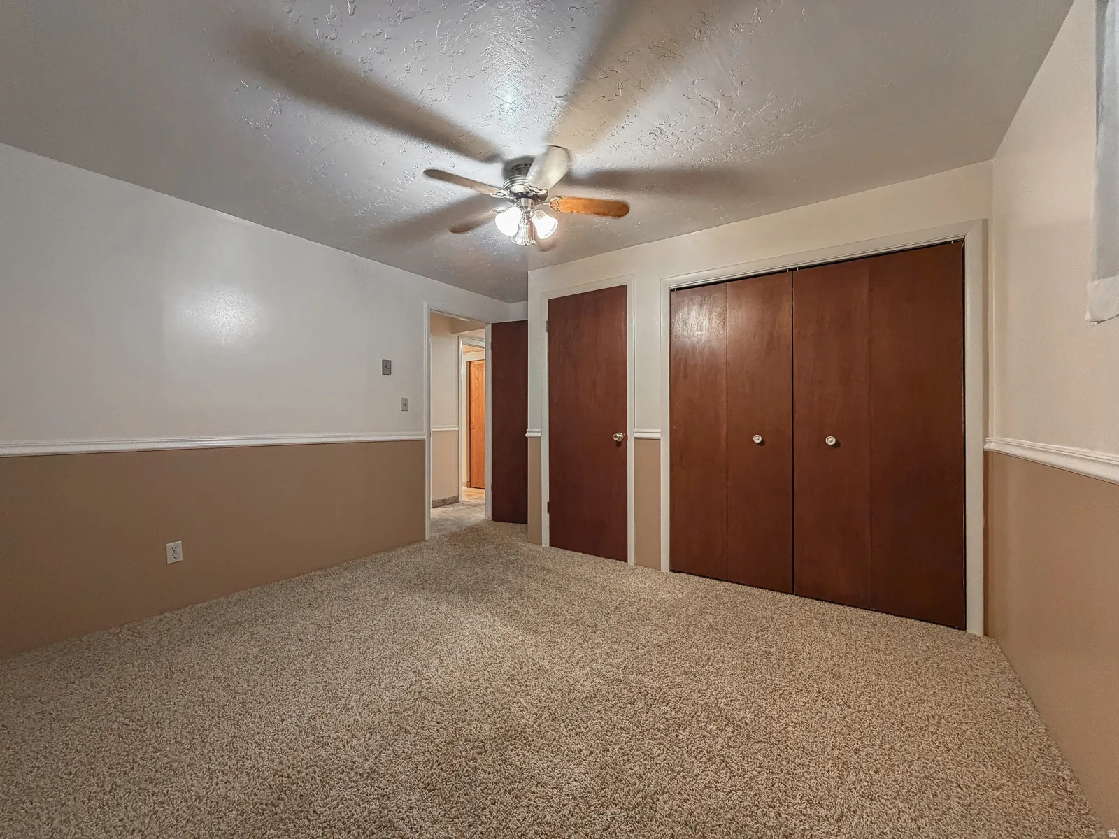 Soft beige wall-to-wall carpeting complements the two-tone wall treatment with a white upper section and beige wainscoting