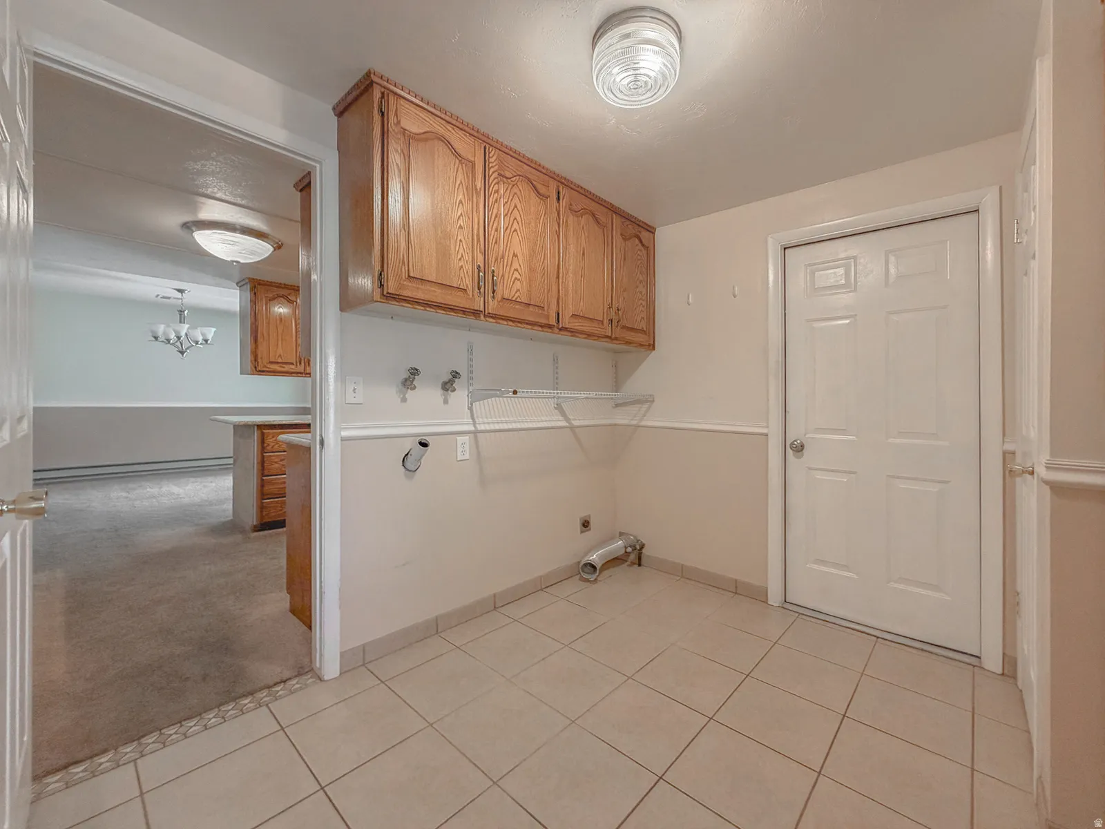 Utility area featuring light wood-finish cabinetry, tile flooring, and a white paneled door