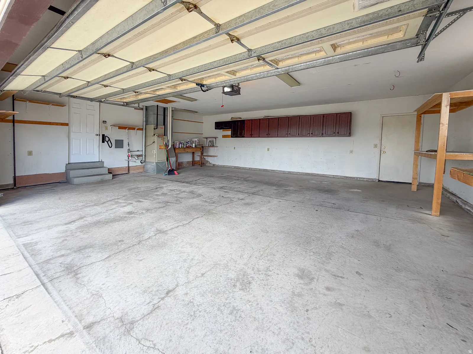 Spacious garage featuring a concrete floor, built-in overhead cabinetry, and integrated shelving