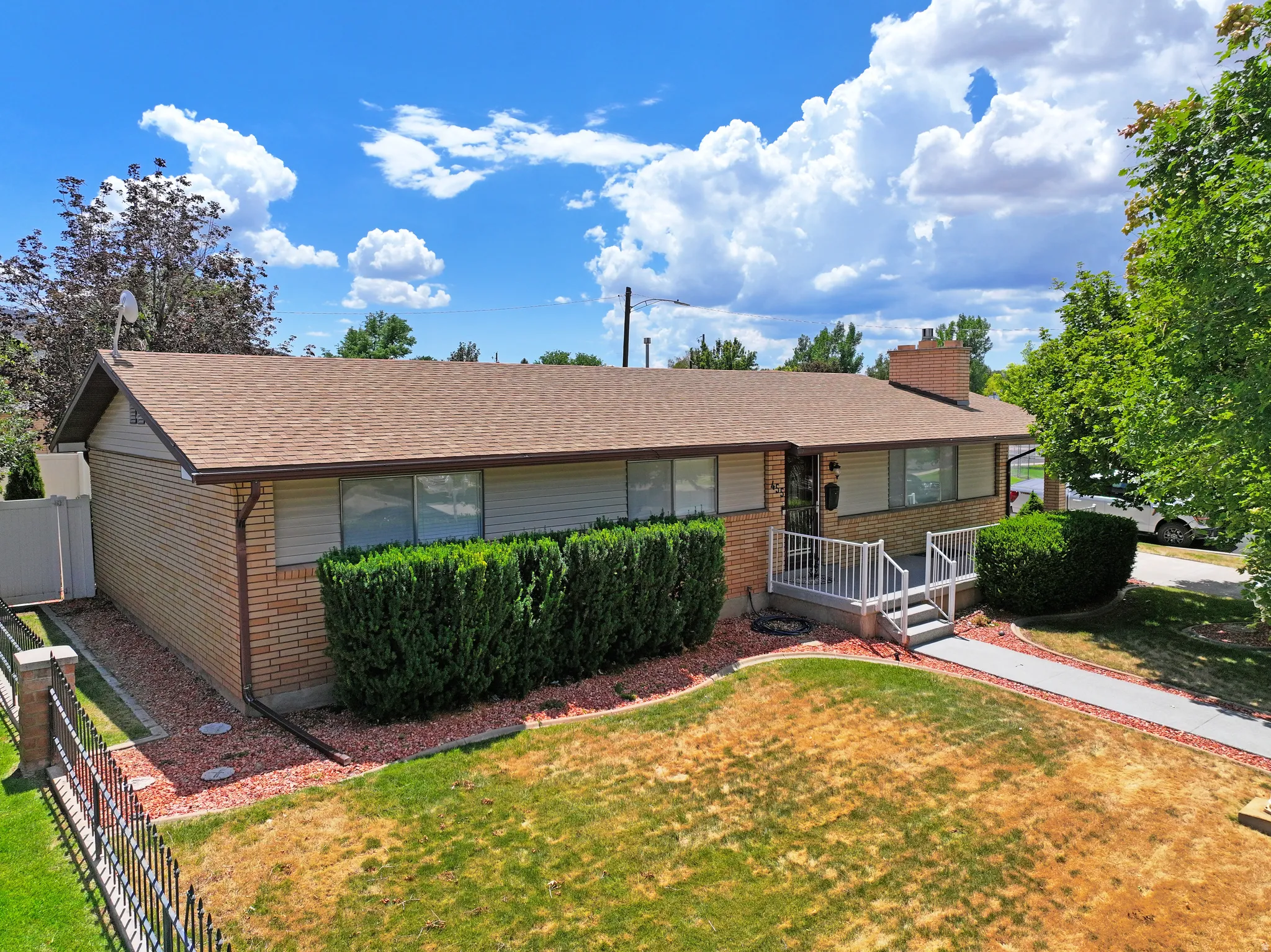 Ranch-style exterior featuring a brick facade, gabled roofline, and established front landscaping
