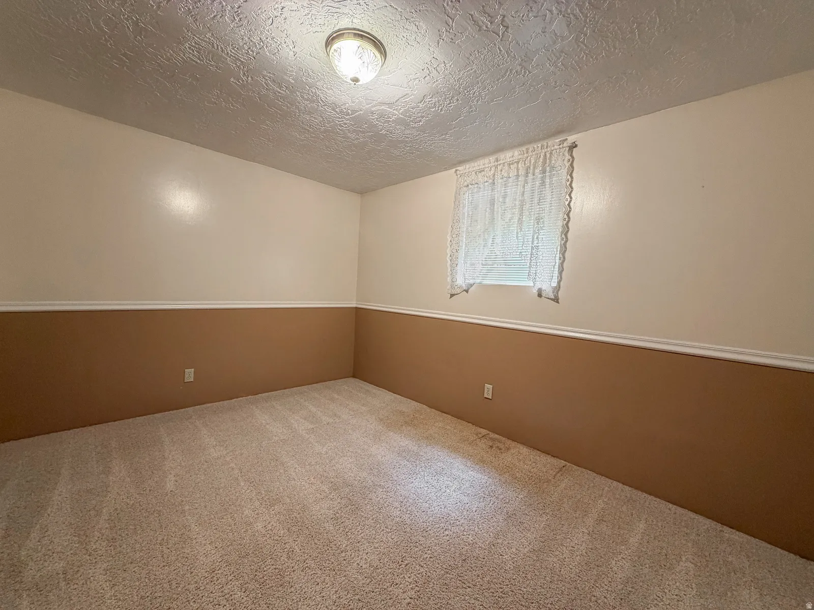 Neutral-toned carpeted flooring complements the two-tone wall design featuring a decorative chair rail