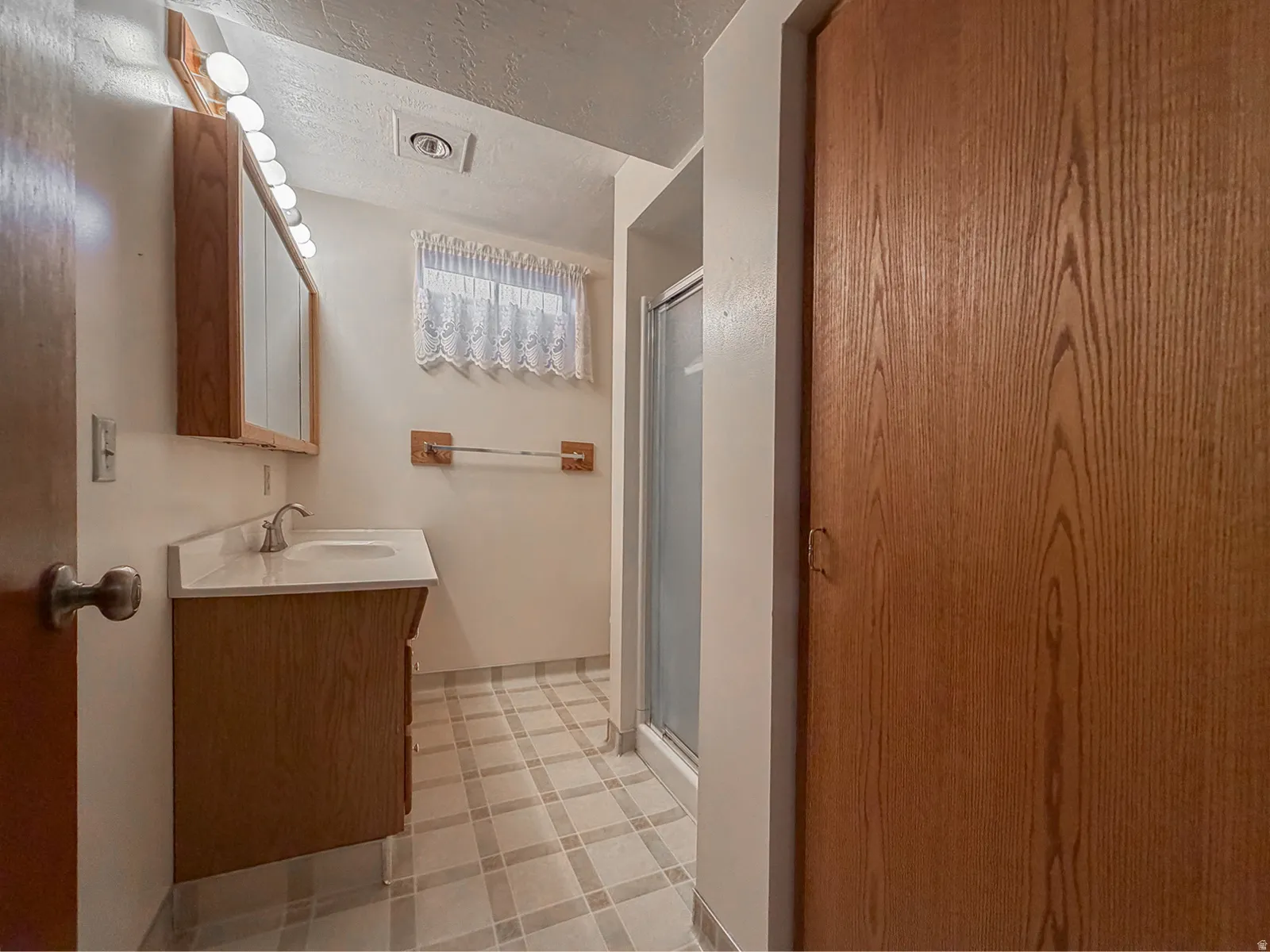Bathroom featuring a wood-finish vanity with an integrated sink and light-colored countertop