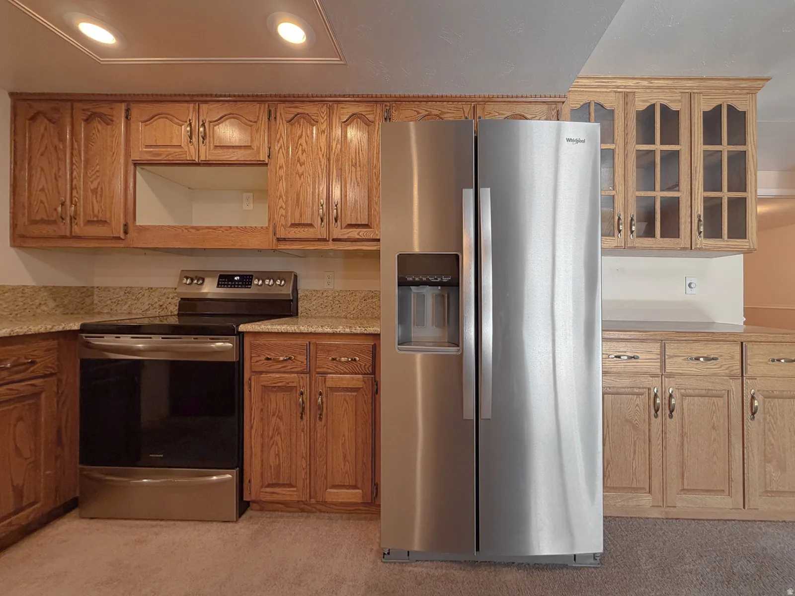 Kitchen featuring wood cabinetry, light-toned countertops, a stainless steel side-by-side refrigerator, and a stainless steel electric range