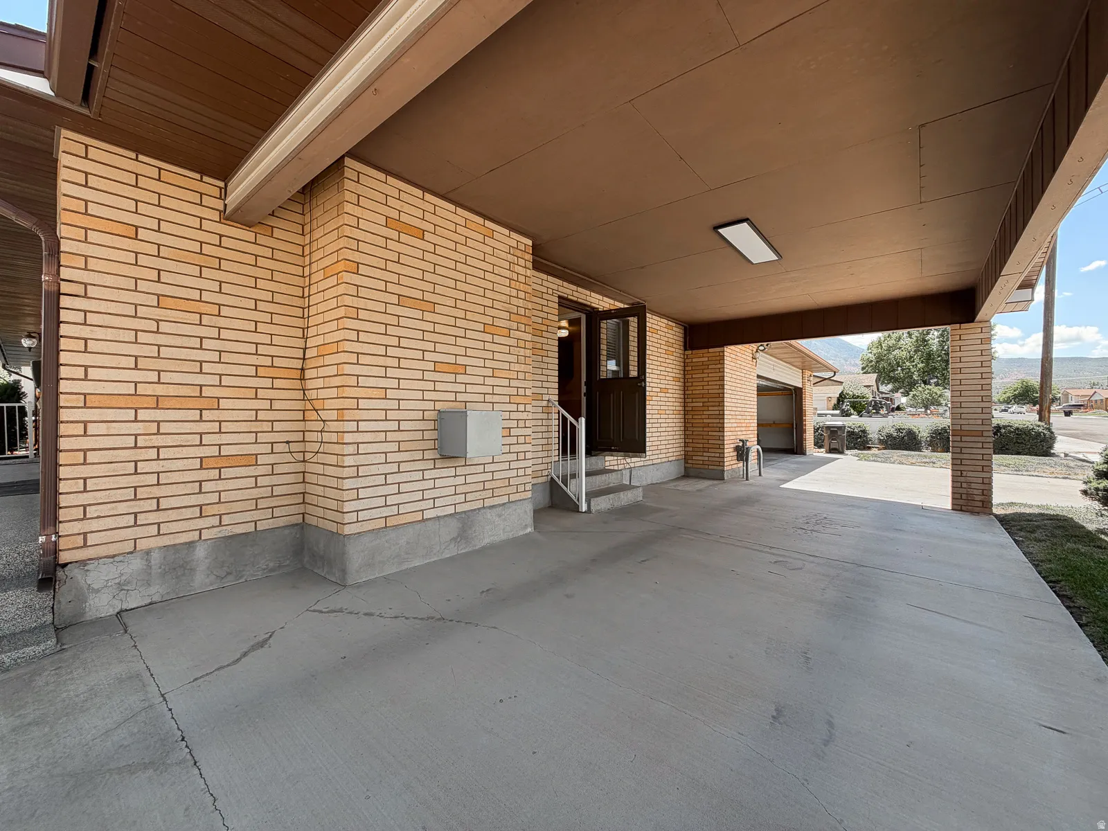 Covered carport with concrete flooring and a linear light fixture
