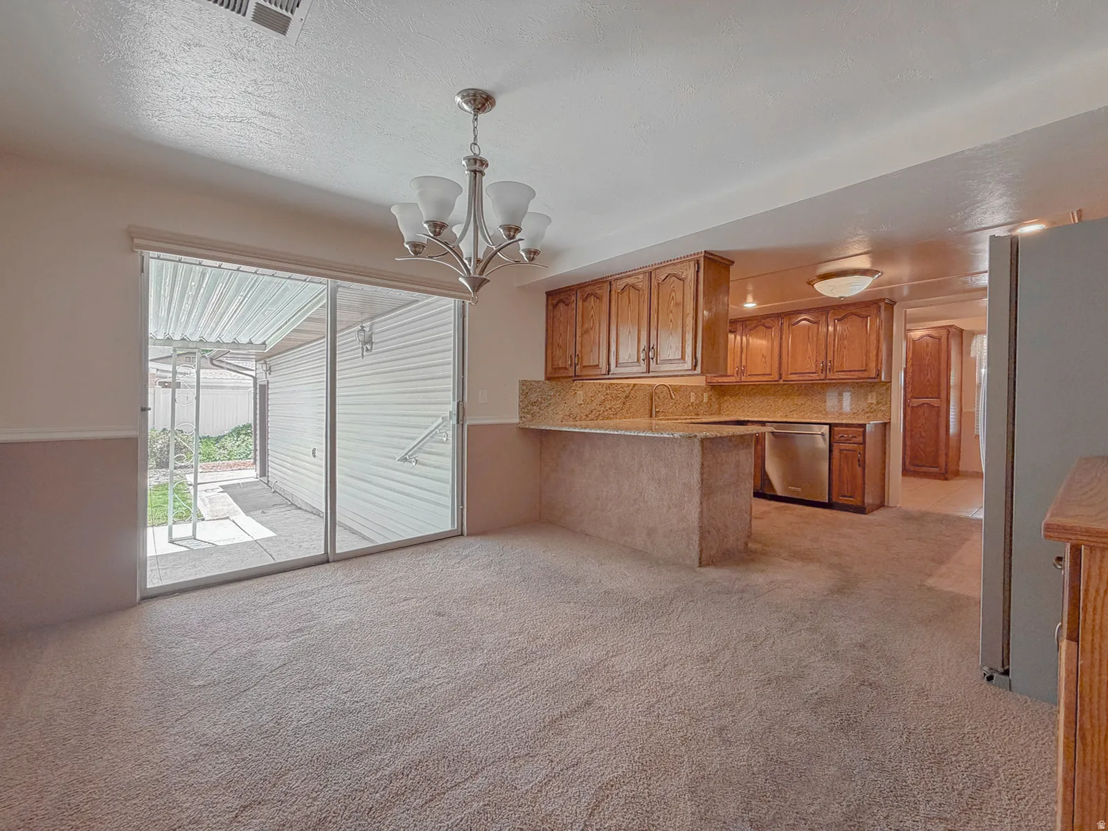 Open-concept living space featuring neutral carpeting, a chandelier, and sliding glass doors to the exterior