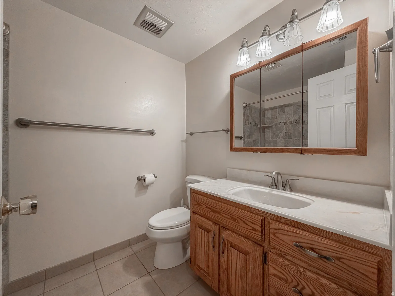 Bathroom featuring a wood-finish vanity with an integrated sink and a white countertop