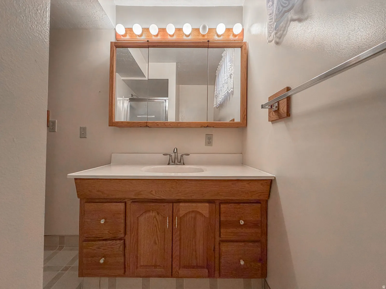 Bathroom vanity featuring a wood-finish cabinet with multiple drawers and a white countertop with an integrated sink