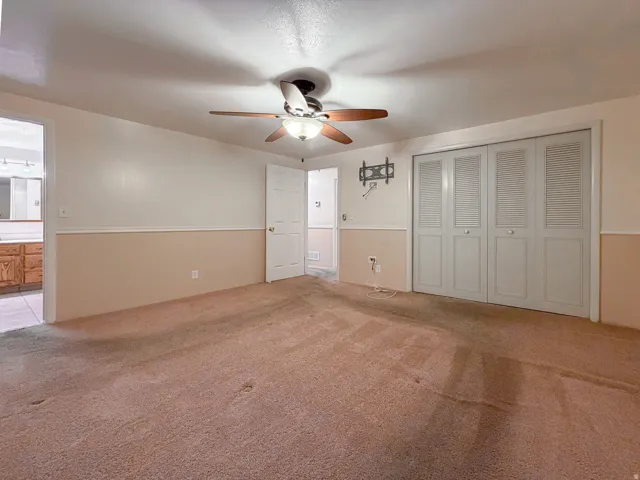 Carpeted room with a ceiling fan light fixture, bi-fold closet doors, and two-tone wall paneling