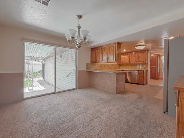 Open-concept living space featuring neutral carpeting, a chandelier, and sliding glass doors to the exterior