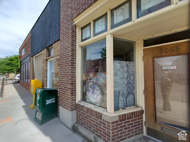 Commercial storefront featuring a brick facade with a large display window and a wood-paneled entry door