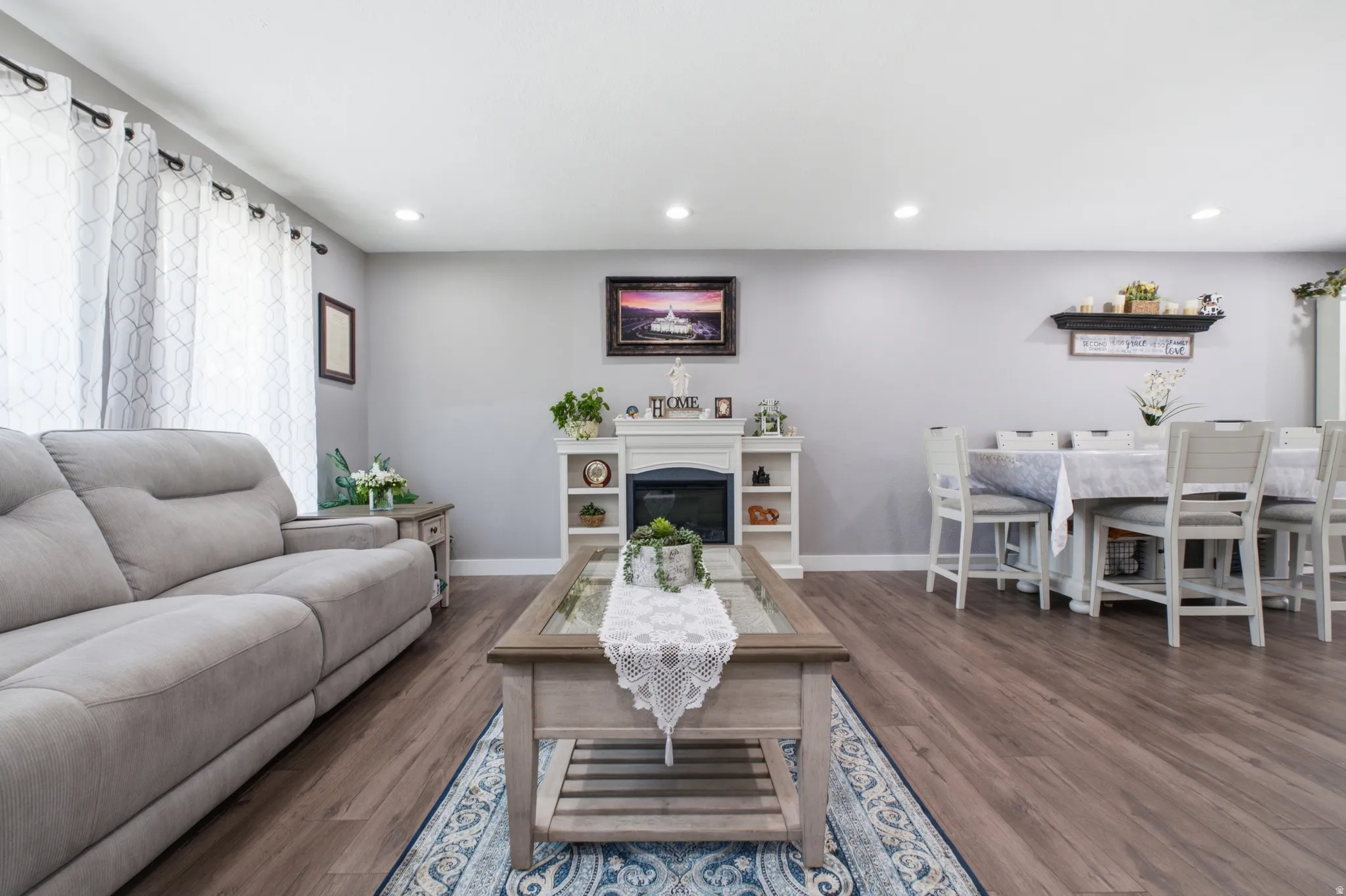 Open-concept living space featuring wood-finish flooring, recessed lighting, and a built-in electric fireplace with surrounding shelving