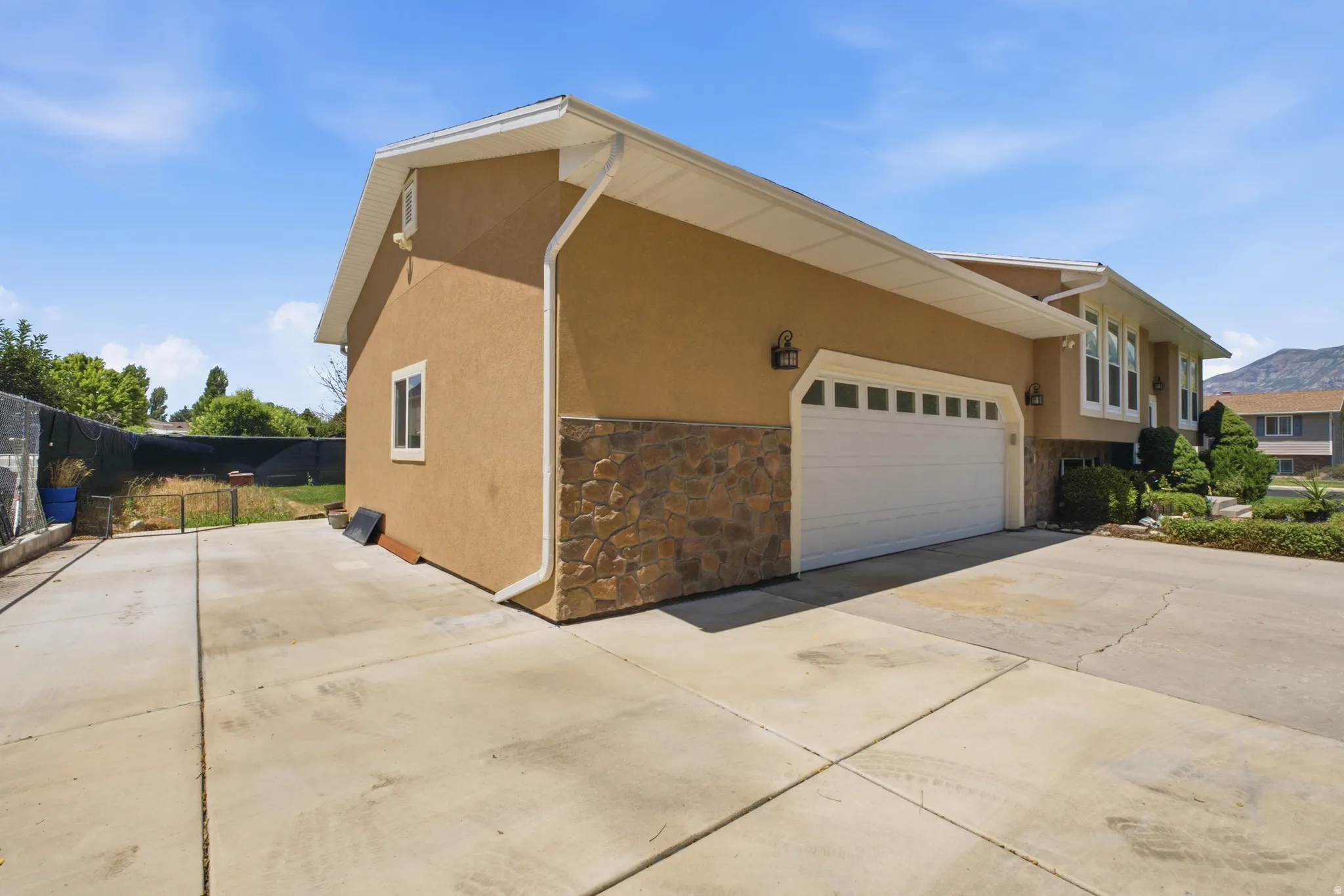 Stucco exterior with stone veneer accents, multi-panel garage door, and a concrete driveway