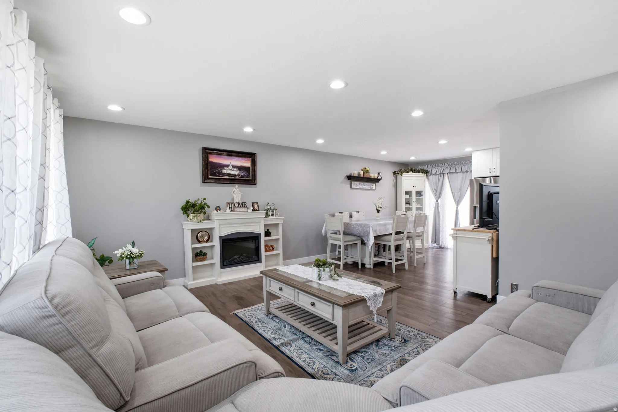 Spacious living area featuring wood-finish flooring, recessed lighting, and a white fireplace with integrated shelving