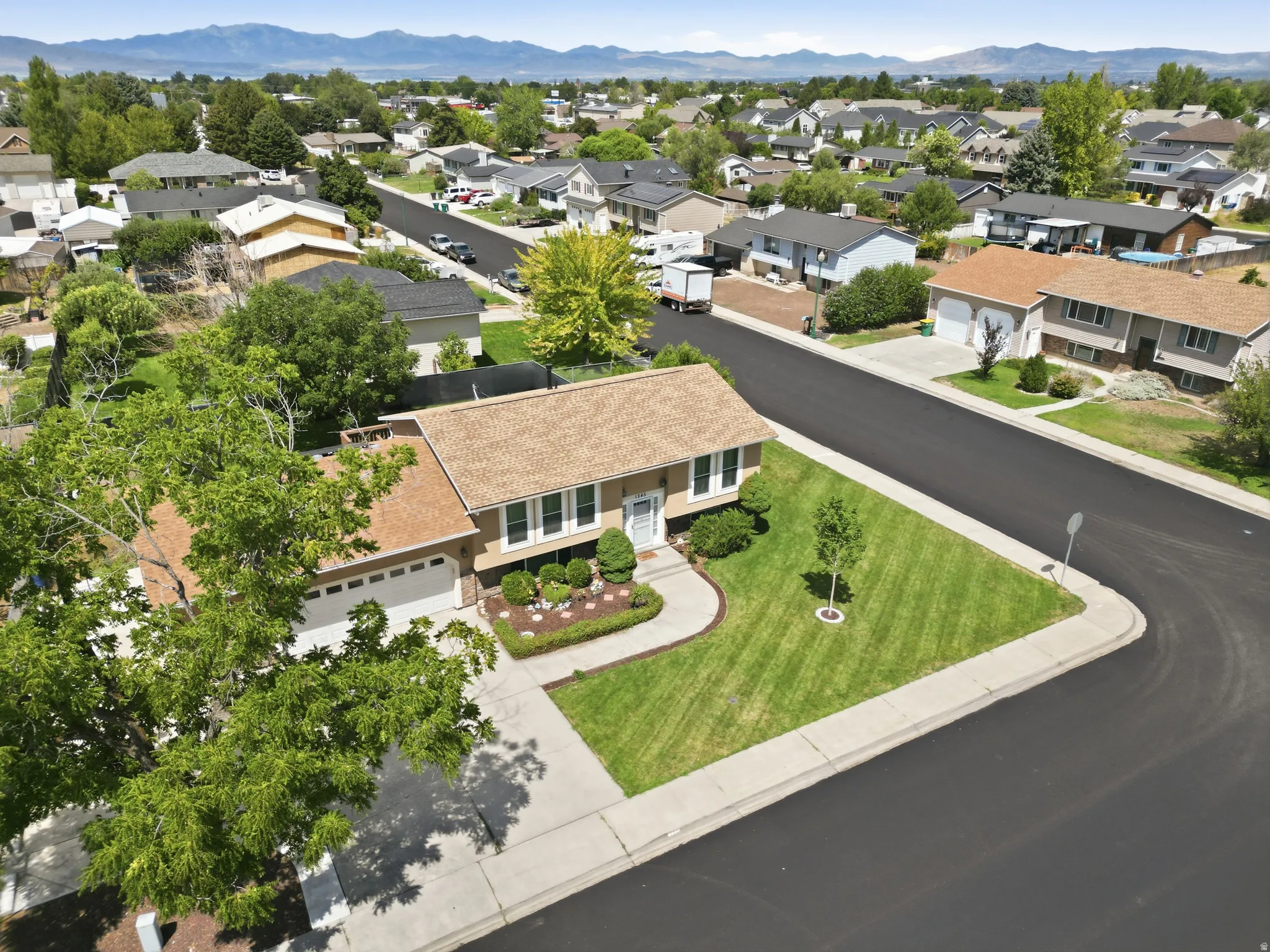 Residential property featuring a tan exterior with white trim, a brown shingle roof, and an attached two-car garage