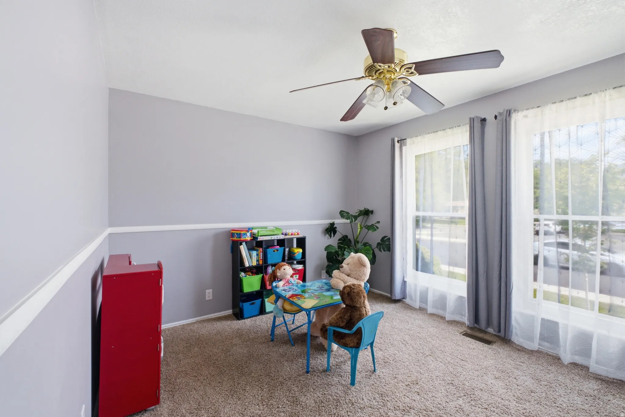 Room featuring two large windows, a ceiling fan with light fixture, and neutral carpeting